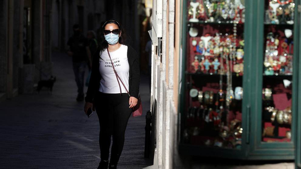 FILE PHOTO: A woman wearing a face mask walks in a street, as Italy begins to ease some of the restrictions of the coronavirus disease (COVID-19) lockdown, in Taormina, Italy, May 12, 2020. REUTERS/Antonio Parrinello