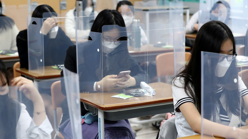 High school students wearing face masks prepare for classes, with plastic covers placed on desks to prevent infection, as schools reopen following the global outbreak of the coronavirus disease (COVID-19), in Daejeon, South Korea, May 20, 2020. Yonhap/via REUTERS ATTENTION EDITORS - THIS IMAGE HAS BEEN SUPPLIED BY A THIRD PARTY. SOUTH KOREA OUT. NO RESALES. NO ARCHIVE.