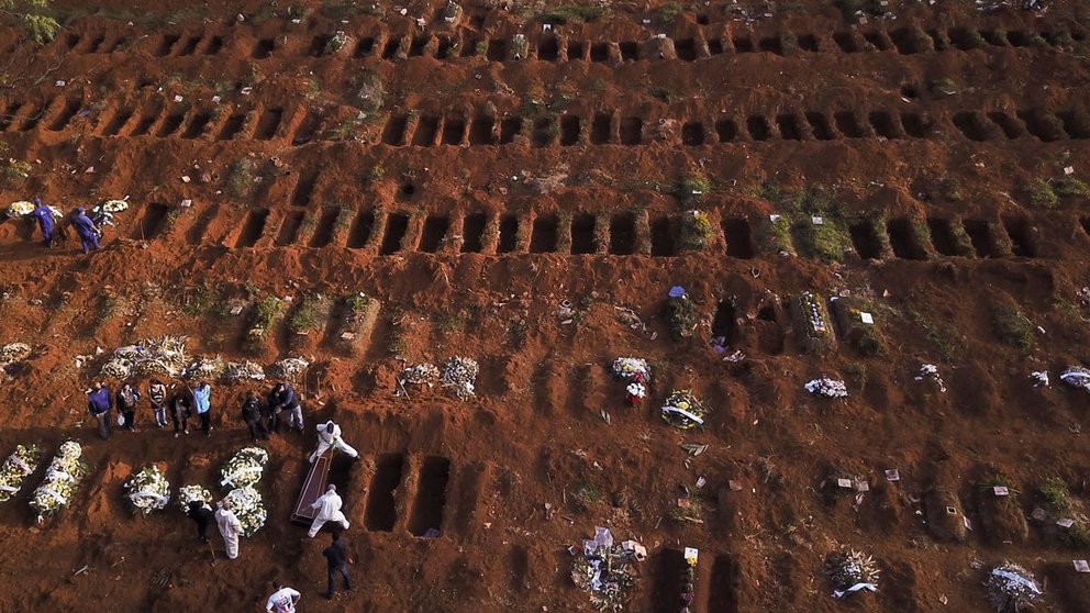 Gravediggers wearing protective suits bury the coffin of a person who died from the coronavirus disease (COVID-19), as open graves are seen at Vila Formosa cemetery, Brazil&#39;s biggest cemetery, in Sao Paulo, Brazil, May 22, 2020. Picture taken with a drone. REUTERS/Amanda Perobelli