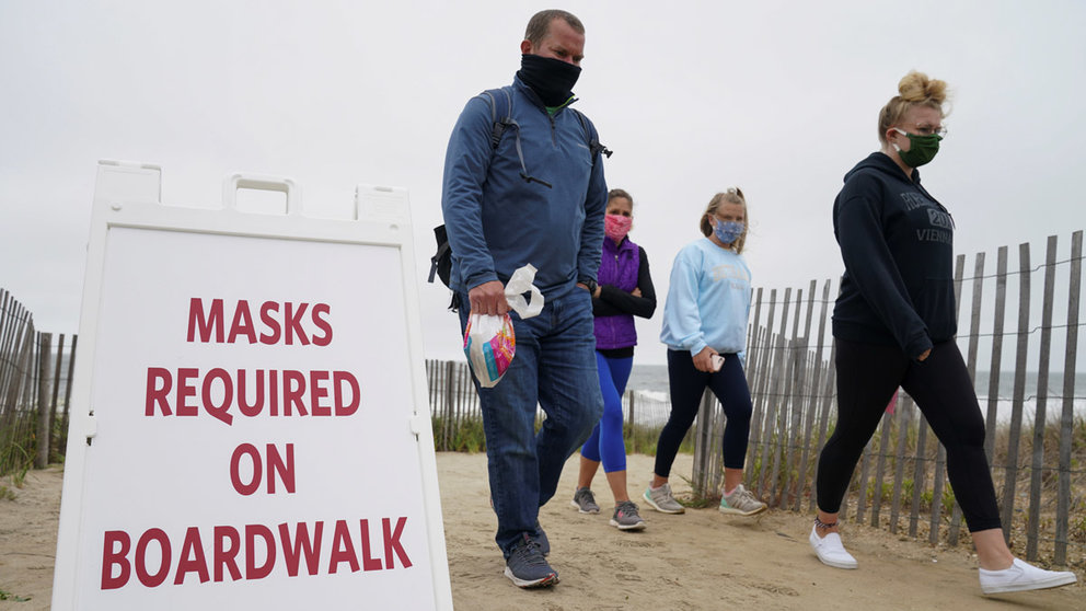 Visitors walk past a sign requiring face masks to stop the spread of the coronavirus disease (COVID-19) during Memorial Day weekend at Bethany Beach, Delaware, U.S., May 24, 2020. REUTERS/Kevin Lamarque