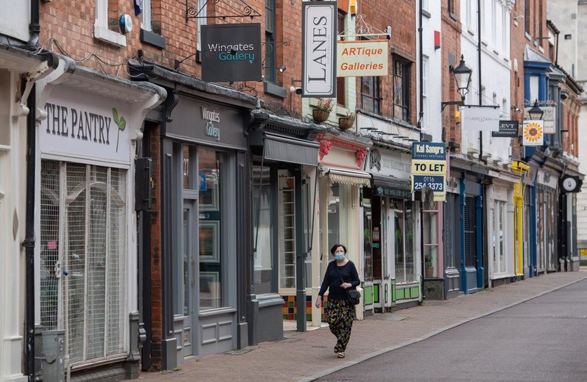 England, Leicester: A woman wearing a face mask walks in front of closed shops at a deserted street where localised coronavirus lockdown restrictions have been in place since 29 June, people were urged not to travel in or out of the area. Photo: Joe Giddens/PA Wire/dpa
