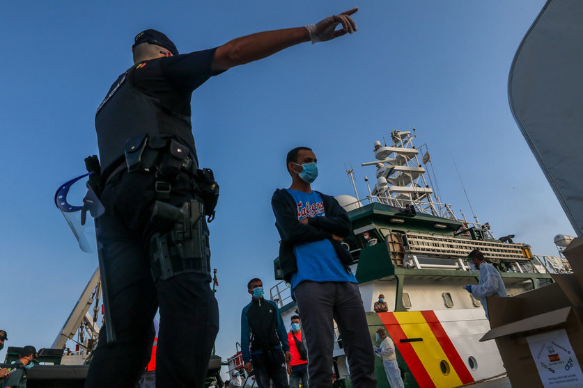 Spain, Malaga: An officer guides a group of immigrants after arriving at the coast of Almeria in Malaga. Photo: dpa.