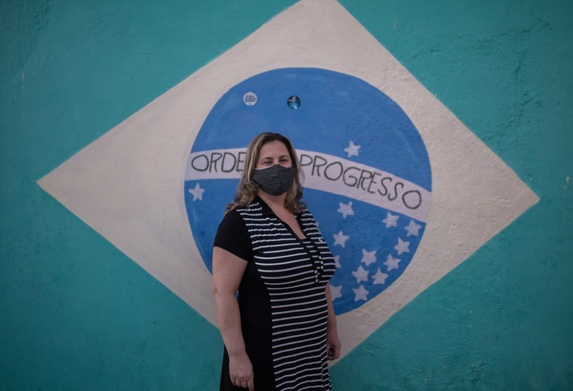 10 August 2020, Brazil, Sao Paulo: Nurse Sarah Aldana Rangon, a volunteer in a study of a possible coronavirus vaccine by Chinese pharmaceutical company Sinovac, poses with a face mask in front of a Brazilian flag painted on a wall. Photo: Andre Lucas/dpa.