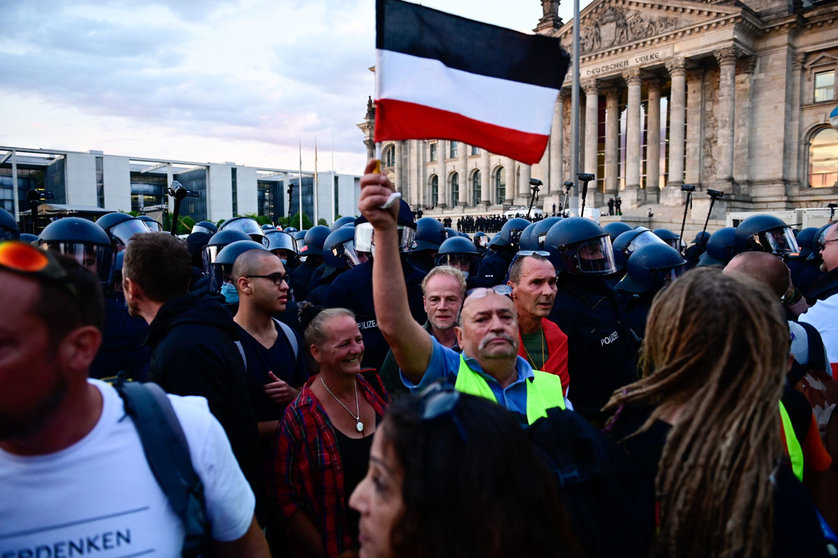 29 August 2020, Berlin: A man holds up the German imperial flag during a demonstration against coronavirus measures. Photo: Fabian Sommer/dpa.