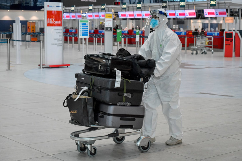 21 December 2020, Czech Republic, Prague: A passenger is seen wearing full protective equipment as he walks with his luggage at Vaclav Havel Airport Prague. The Czech Republic has announced an immediate ban on flights from and to Britain over the recently discovered variant of the coronavirus. Photo: Vít imánek/CTK/dpa