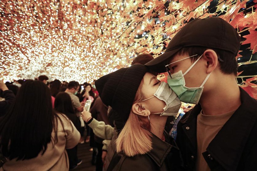 18 December 2020, Taiwan, New Taipei City: A couple wear face masks as they kiss in an autumn leaves decoration at the foot bridge before the Christmas. Photo: Daniel Ceng Shou-Yi/ZUMA Wire/dpa