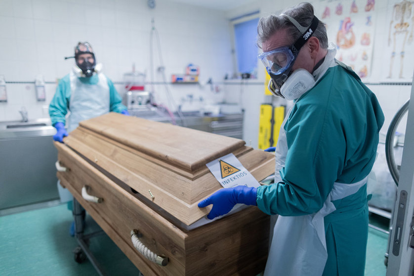 FILED - Christoph Kuckelkorn (r), funeral director and president of the Cologne Carnival Festival Committee, and an employee close a coffin containing a deceased person who died of or with the coronavirus. Both wear protective suits and respirators. For Kuckelkorn, the corona pandemic is palpable. "We have perceptibly a significant increase in corona deaths," Kuckelkorn told the German Press Agency. Photo: Rolf Vennenbernd/dpa