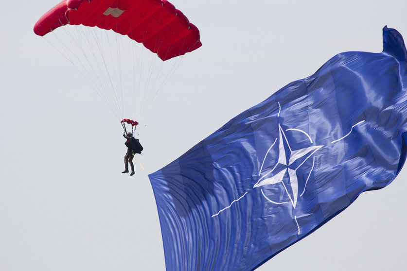 A paratrooper waves the NATO flag during a jump. Photo: Pixabay.
