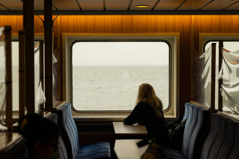dpatop - 22 February 2021, Lower Saxony, Norderney: A woman sits at a window of the ship during the crossing with the North Sea ferry Frisia from Norddeich to Norderney and looks at the North Sea (to dpa "Tourism figures 2020 for Lower Saxony). Photo: Mohssen Assanimoghaddam/dpa