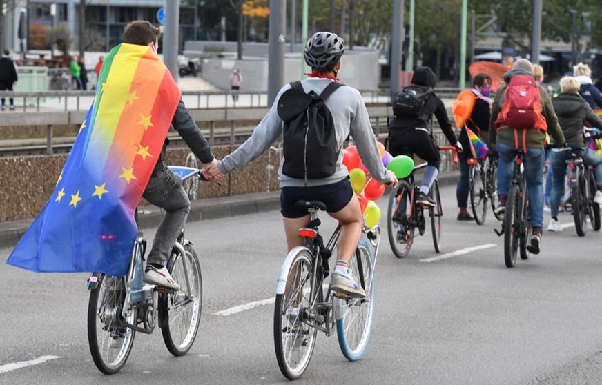 FILED - Participants of a bicycle rally of this year's Christopher Street Day (CSD) cycle through the city of Cologne with a rainbow flag. Instead of a large parade, which fell victim to the Corona pandemic, lesbians, gays and transsexuals marched through the streets in a bicycle demonstration during Corona Year to protest for their cause. Photo: Roberto Pfeil/dpa