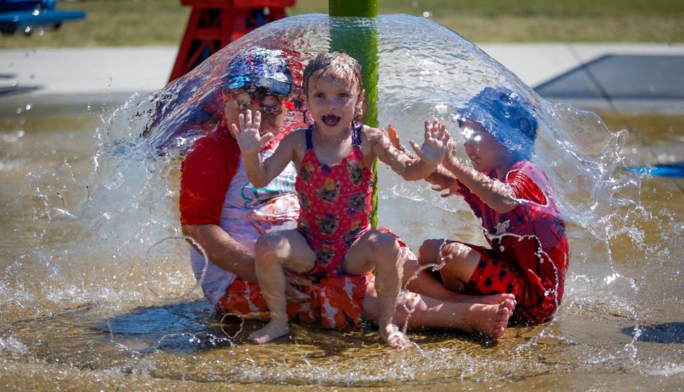 28 June 2021, Canada, Olds: Poppy Collins (C), five, sits under a water umbrella to try and beat the heat at a splash park. Environment Canada warns the torrid heat wave that has settled over much of Western Canada won't lift for days. Photo: Jeff Mcintosh/The Canadian Press via ZUMA/dpa