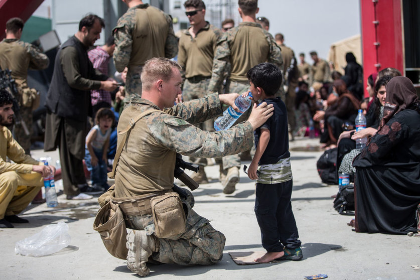 20 August 2021, Afghanistan, Kabul: A US Marine soldier provides fresh water to a child as Afghan civilians wait to board an aircraft during the evacuation process at Hamid Karzai International Airport. Photo: -/US Marines via ZUMA Press Wire Service/dpa
