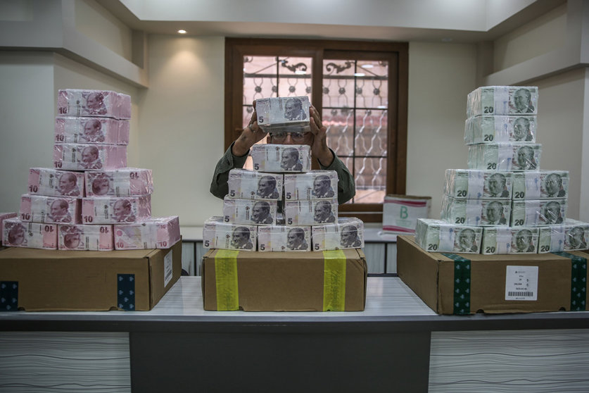FILED - An employee piles up stacks of Turkish lira banknotes inside a bank at the northern Syrian town of Sarmada in 2020. Turkey's currency hit yet another record low of over 14 against the dollar before recouping some losses on Wednesday after a central bank move to sell reserves. Photo: Anas Alkharboutli/dpa.