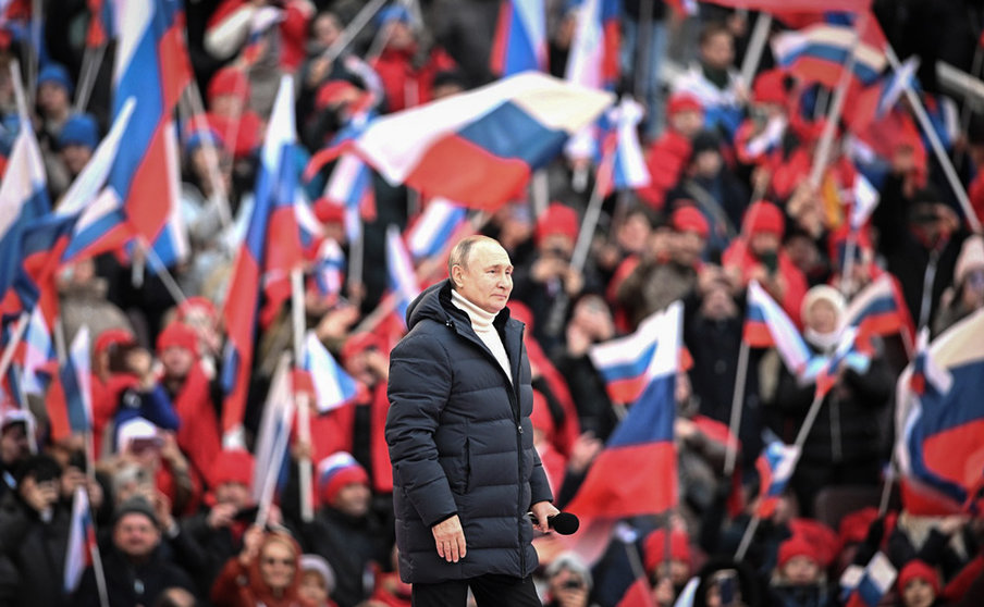 HANDOUT - 18 March 2022, Russia, Moscow: The crowd waves Russian flags as Russian President Vladimir Putin walks to deliver a speech during a concert held to mark the eighth anniversary of Russia's annexation of Crimea at the Luzhniki stadium. Photo: -/Kremlin/dpa - ATTENTION: editorial use only and only if the credit mentioned above is referenced in full.